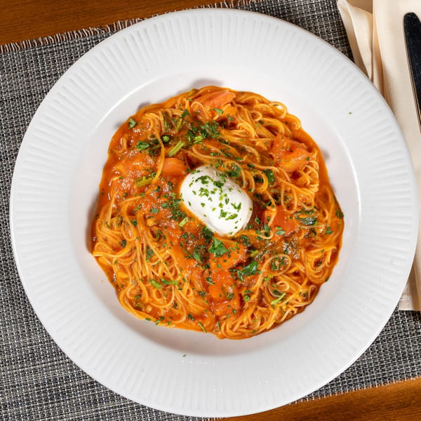 Spaghetti with tomato sauce, shrimp, and a dollop of white cream cheese, garnished with parsley.