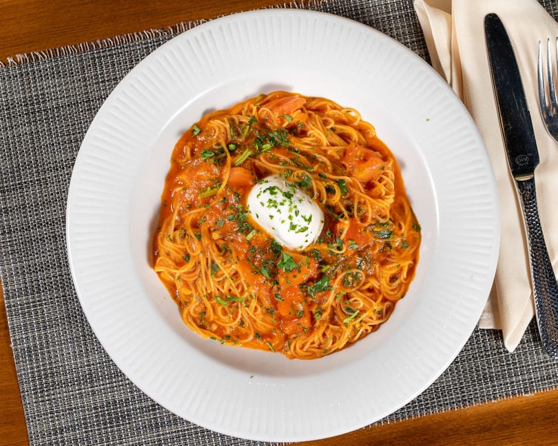 Spaghetti with tomato sauce, shrimp, and a dollop of white cream cheese, garnished with parsley.