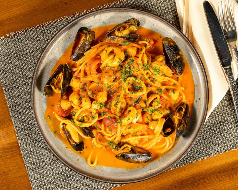 Seafood pasta with mussels, calamari, and scallops in a rich tomato sauce, garnished with parsley.