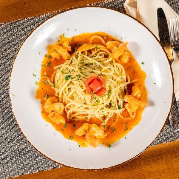 Spaghetti with shrimp in a red sauce, garnished with parsley and a tomato flower.